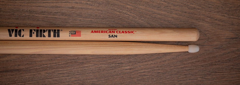 https://www.drumazon.com/cdn/shop/products/VIC-FIRTH-AMERICAN-CLASSIC-HICKORY-5A-NYLON-TIP-VF-5AN-DRUM-STICKS-DRUMAZON_02_1000x.jpg?v=1613922588